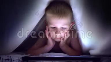 年轻的金发男孩在平板电脑上玩电脑游戏。